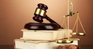 Golden scales of justice, gavel and books on brown background